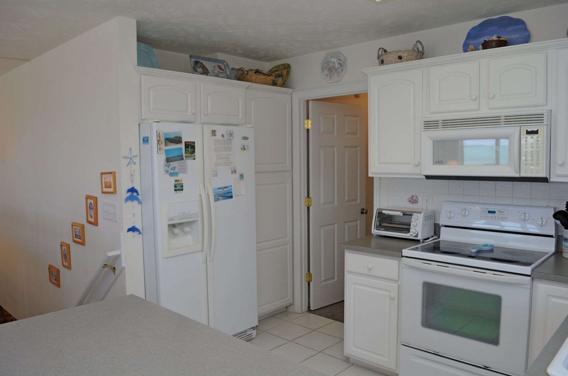 A kitchen with white cabinets, a refrigerator, a microwave, a toaster, and an oven.