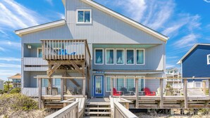 Ein zweistöckiges Strandhaus mit Balkon, Liegestühlen und freiem Blick auf den Ozean.