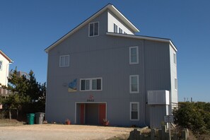 A two-story building with a flat roof, a red door, and a sign indicating a number. - Time in a Bottle Oceanfront, Spacious 6 bedroom in Surf City! (Surf City)