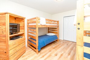 Ein Etagenbett mit einem Fernseher auf einer Holzkombination, einer Tür und einem Holzschrank.
