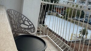 A balcony with a metal railing, two chairs, and a small table.