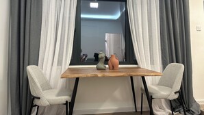 A room with a window, two chairs, a table, and a vase.