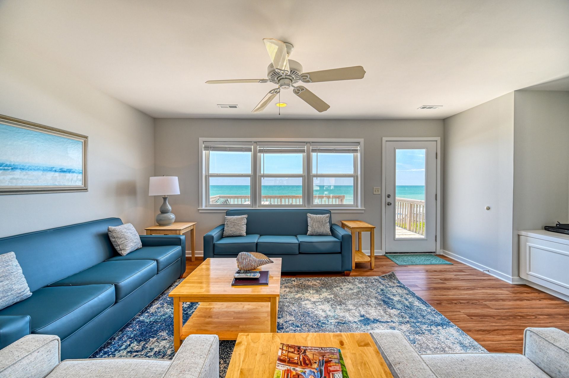 A living room with a blue sofa, a coffee table, and a ceiling fan.