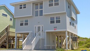 A two-story building with a front porch and a staircase leading to the entrance. - What A View: Oceanfront 6-bedroom home in Surf City perfect for families. (Surf City)
