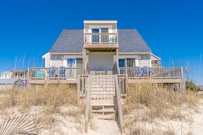 A two-story beach house with a wooden deck and a staircase leading to the entrance. - Whittington - Oceanfront 3-Bedroom, perfect for family getaways! (North Topsail Beach)