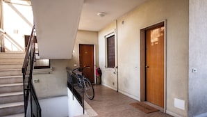 Um corredor com escadas, portas de madeira e uma bicicleta encostada na parede.