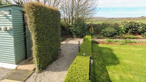 A garden pathway leading to a shed, surrounded by well-maintained hedges and a grassy lawn. - Higher Merther Farm Shepherds Hut (Helston)
