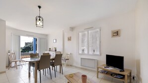 Un salon moderne avec un coin repas, un téléviseur posé sur un meuble en bois et un balcon avec vue.