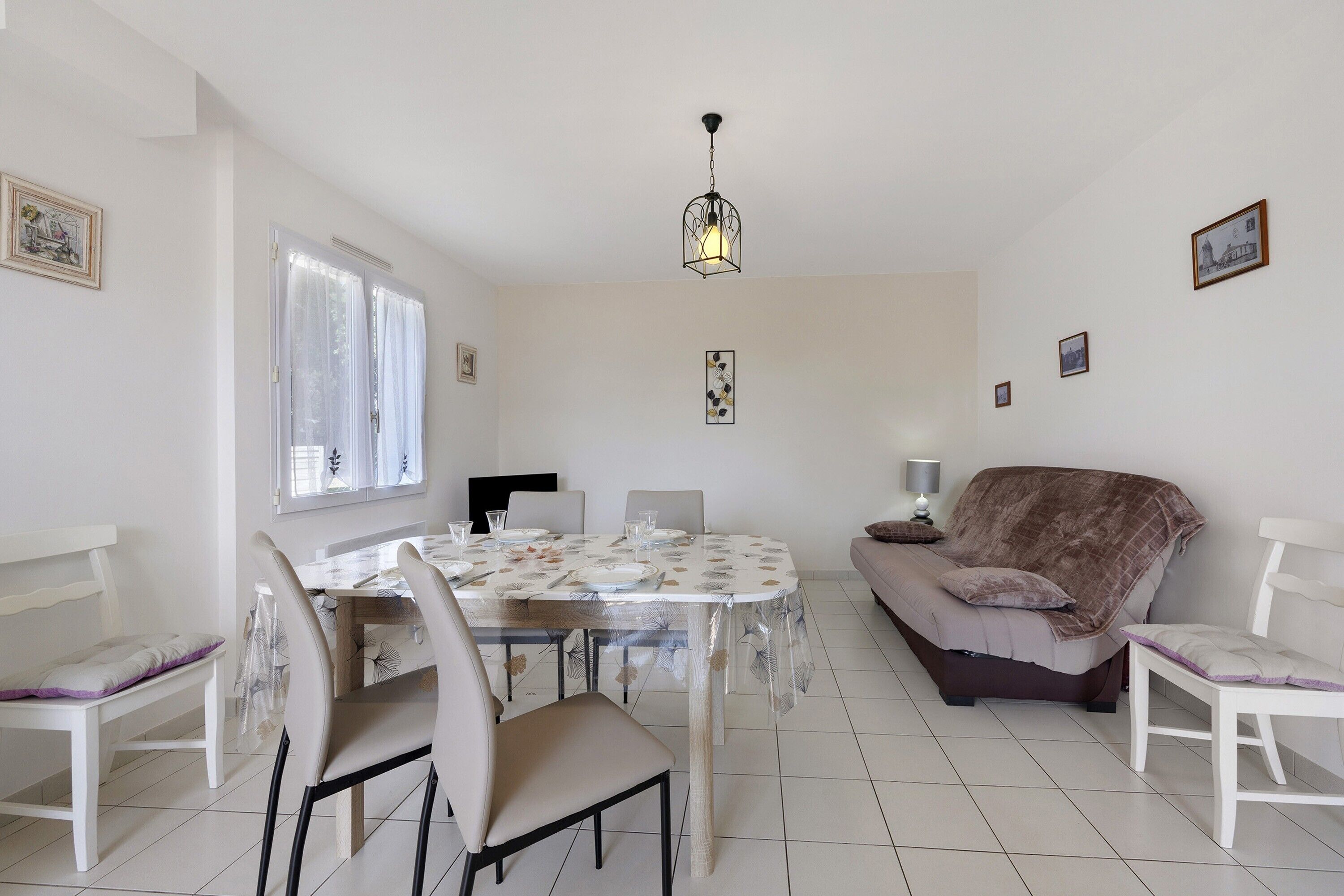 Un espace repas comprenant une table, des chaises et un luminaire suspendu.