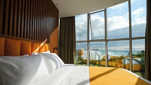 A hotel room with a large window, a bed, and a view of a bridge and cityscape. - Calligraphy Hotel (Batumi)