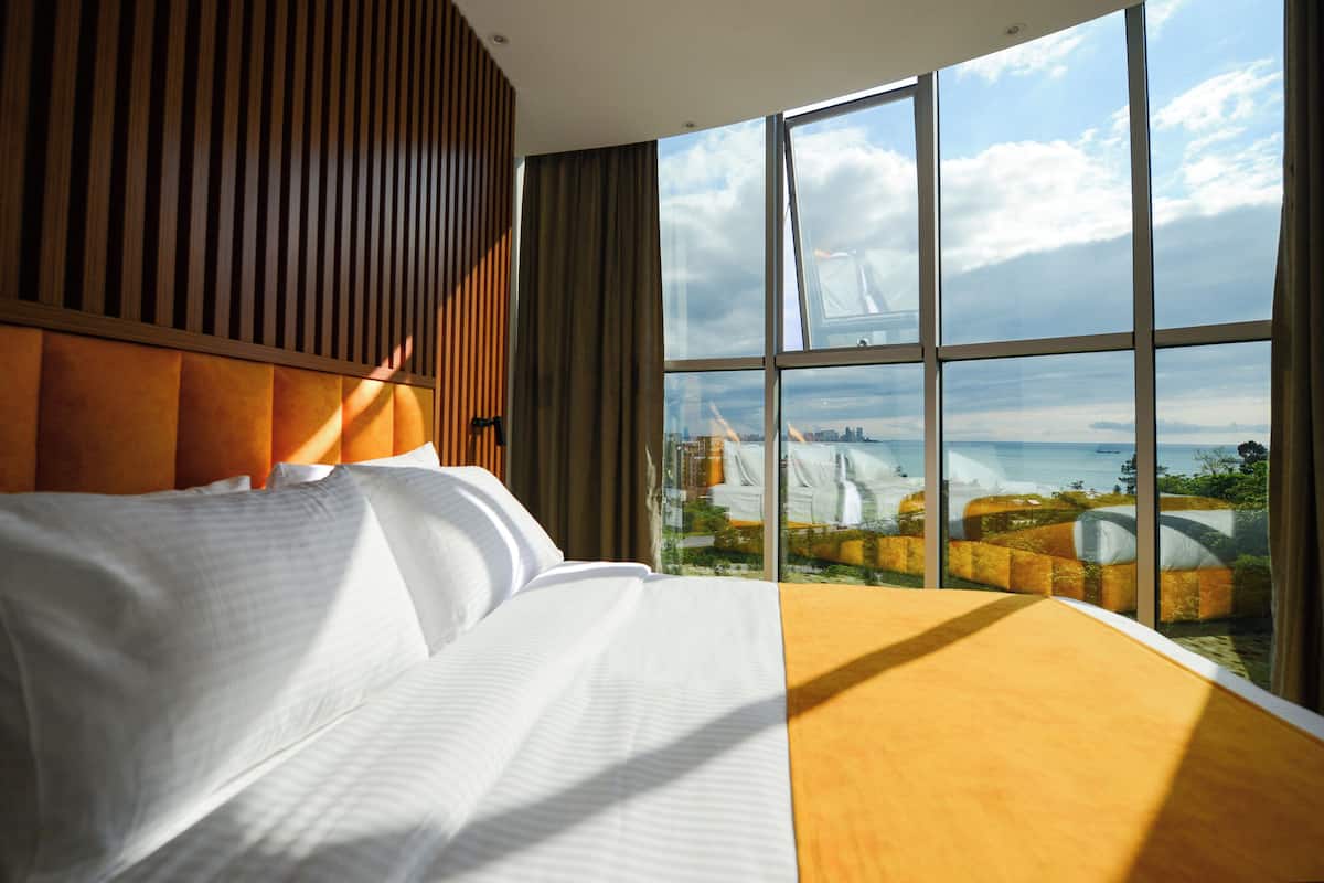 Ett hotellrum med ett stort fönster, en säng och utsikt över en bro och stadens silhuett.