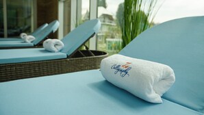 A hotel room with a blue bed, a white towel with 'Calligraphy' embroidered on it, and a wicker basket. - Calligraphy Hotel (Batumi)