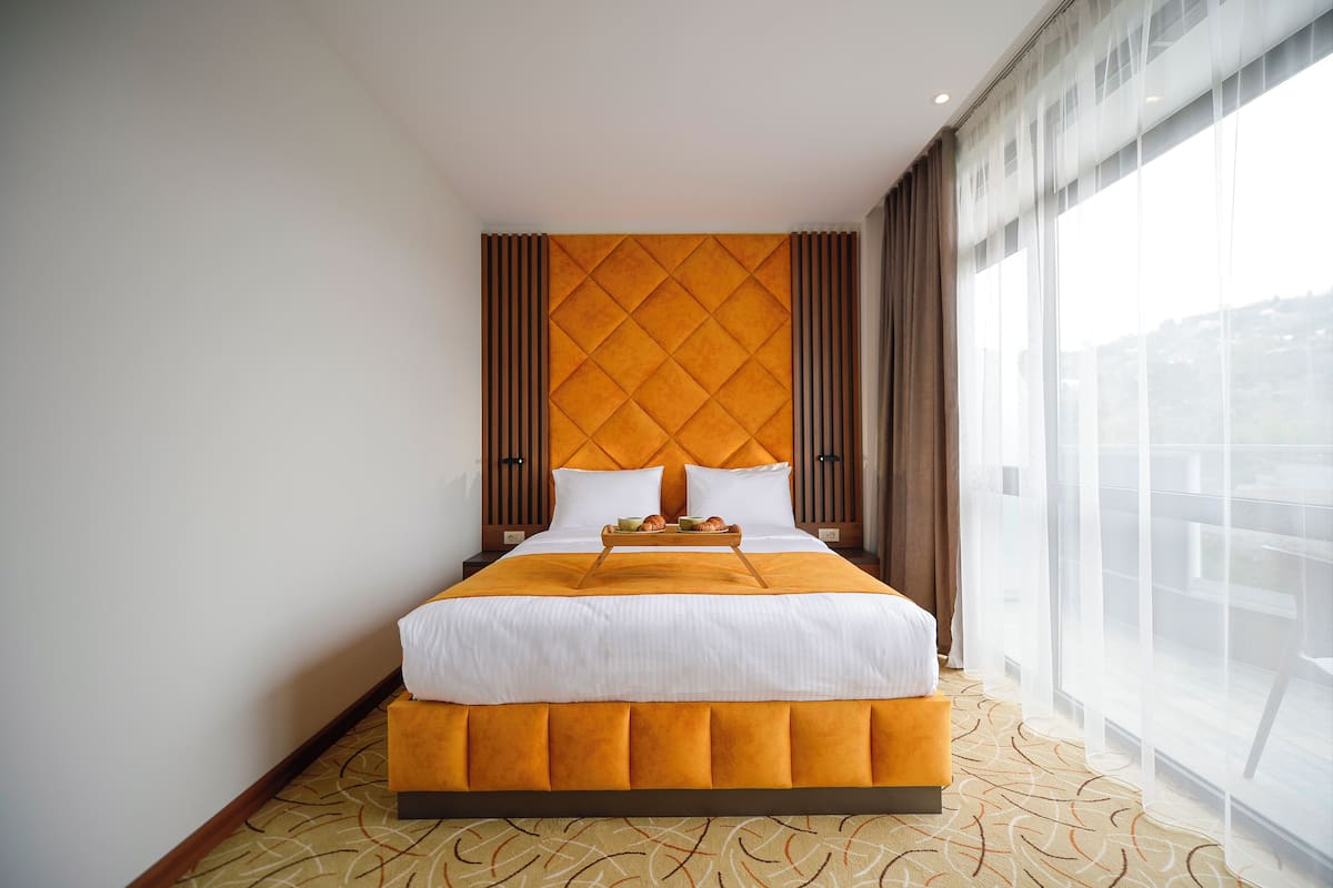 Ett hotellrum med en stor säng, utsikt över staden och en modern design.