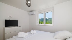 Une chambre d’hôtel avec un lit, un téléviseur posé sur une commode, une fenêtre donnant sur les montagnes et un appareil de climatisation.