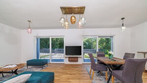 Un salon moderne comprenant un téléviseur, un canapé, une table à manger et des chaises.