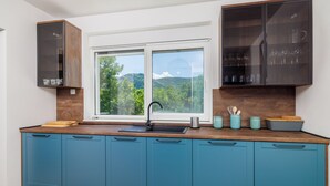 Une cuisine moderne dotée d’une grande fenêtre, de meubles bleus et d’un plan de travail en bois.