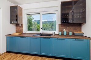 A modern kitchen with a large window, blue cabinets, and a wooden countertop. - Mediterranean villa with 5 bedrooms, pool and large outdoor area (Tribalj)