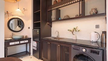 Una cocina moderna con lavadora integrada, un lavamanos y un espejo sobre la encimera.