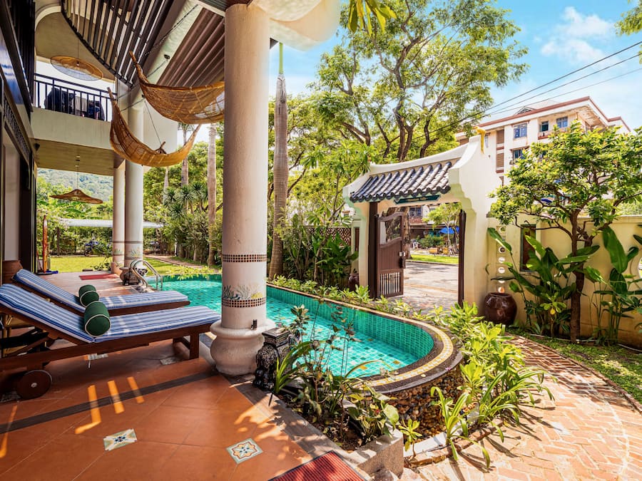 Área de piscina com rede, espreguiçadeiras e piscina revestida em azulejos.