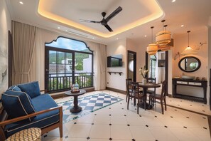 A hotel room with a balcony, a dining area, and a TV mounted on the wall. - Natalie Indochine Mountain Villa Da Nang By Sujet of Haviland (Da Nang)