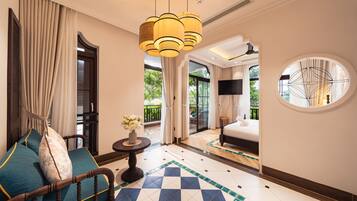 Une chambre d’hôtel avec un sol à carreaux, un lit, un canapé, une table avec un vase de fleurs et une grande fenêtre avec des rideaux.