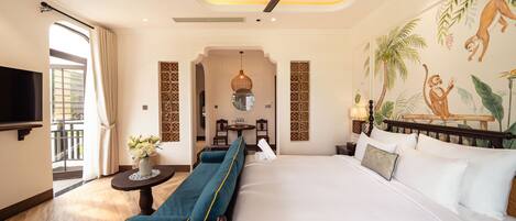 A hotel room with a bed, a sofa, a TV, a ceiling fan, and a mural on the wall.