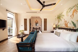 Una habitación de hotel con cama, sofá, televisión, ventilador de techo y un mural en la pared.