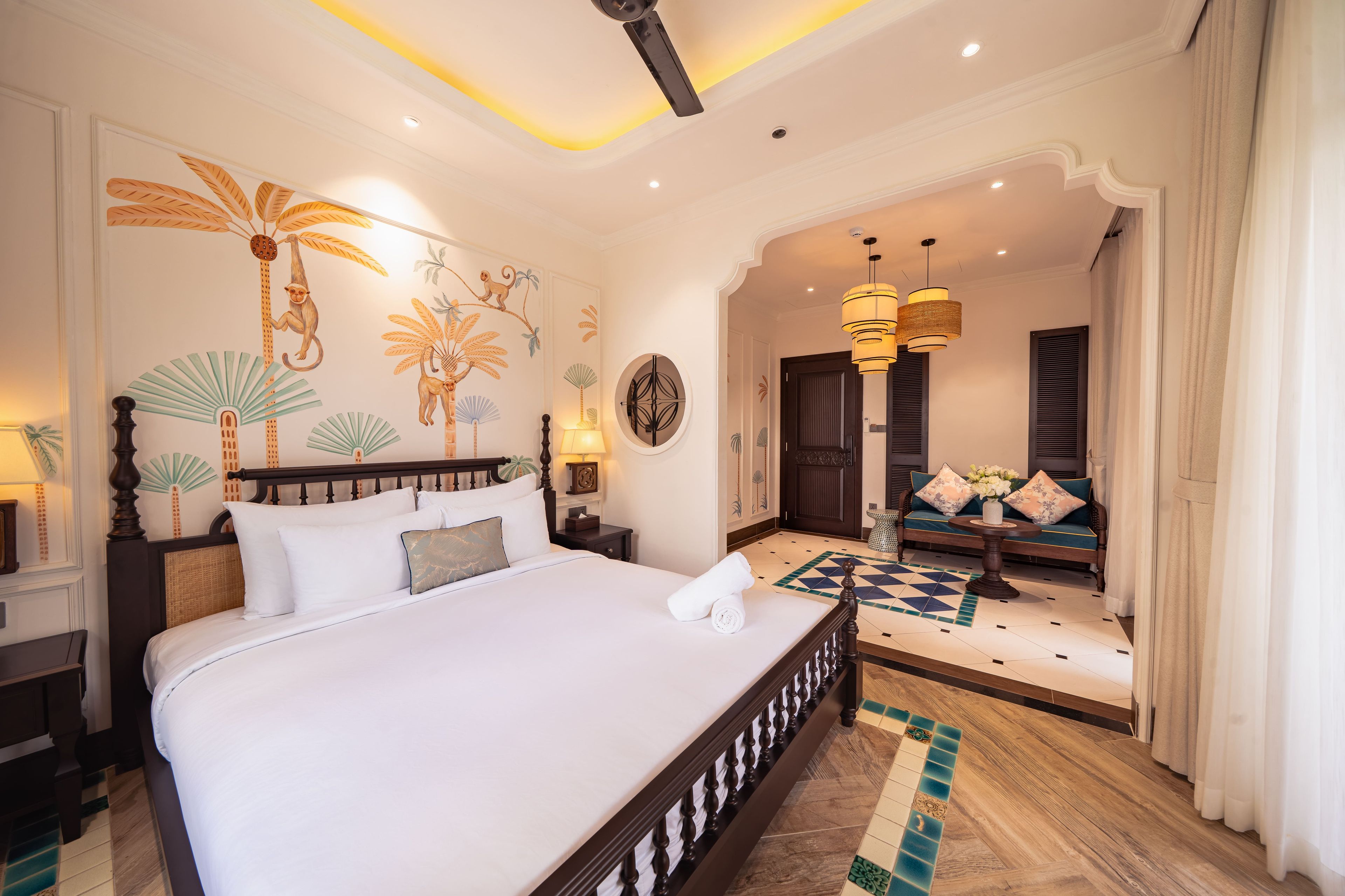 A hotel room with a large bed, a sitting area with a sofa, and a decorative wall mural.