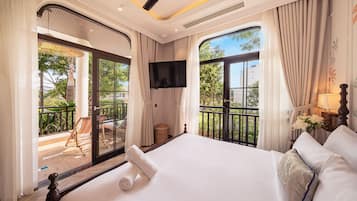 A hotel room with a large bed, a TV, a balcony with a chair, and curtains.