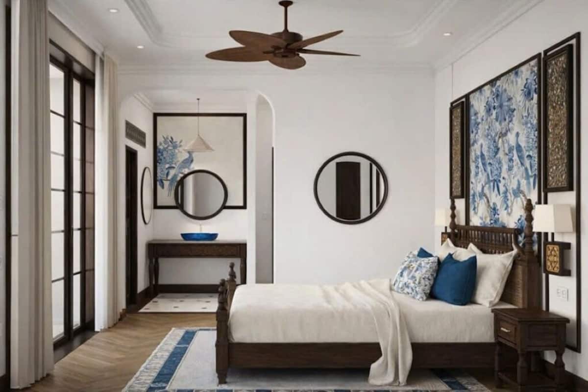 A bedroom with a bed, a ceiling fan, a bedside table, a nightstand, a mirror, and artwork on the walls.