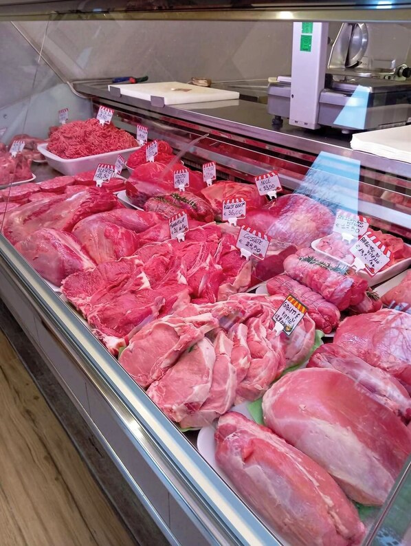 A meat display case in a grocery store with various cuts of meat and price tags. - Agriturismo La Fornace (Senna Comasco)