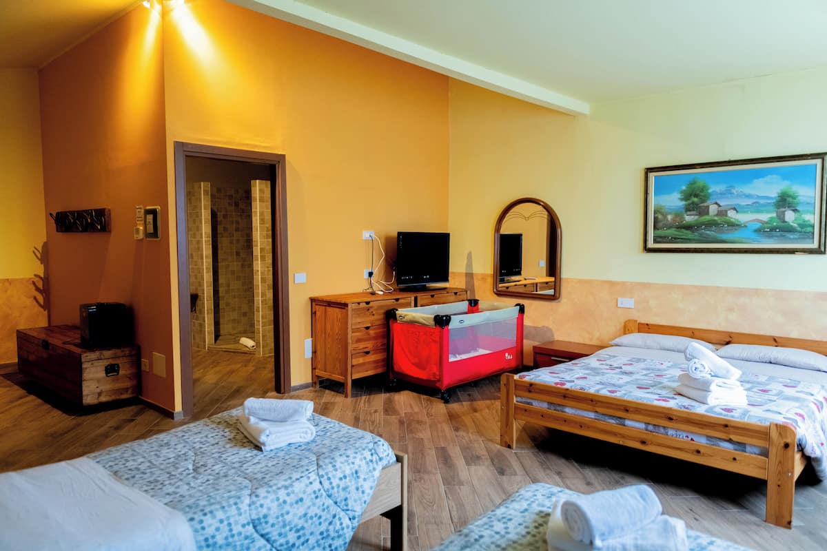 Een hotelkamer met twee bedden, een houten dressoir, een televisie, een rode box en een schilderij aan de muur.