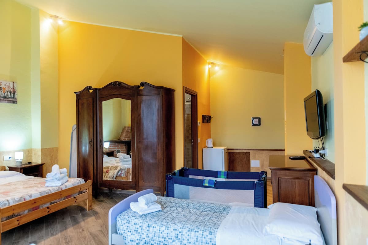Een hotelkamer met twee bedden, een kledingkast, een spiegel, een televisie en een klein bureau.