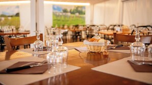 A restaurant interior with tables set for dining, clear glassware, and a basket of bread.