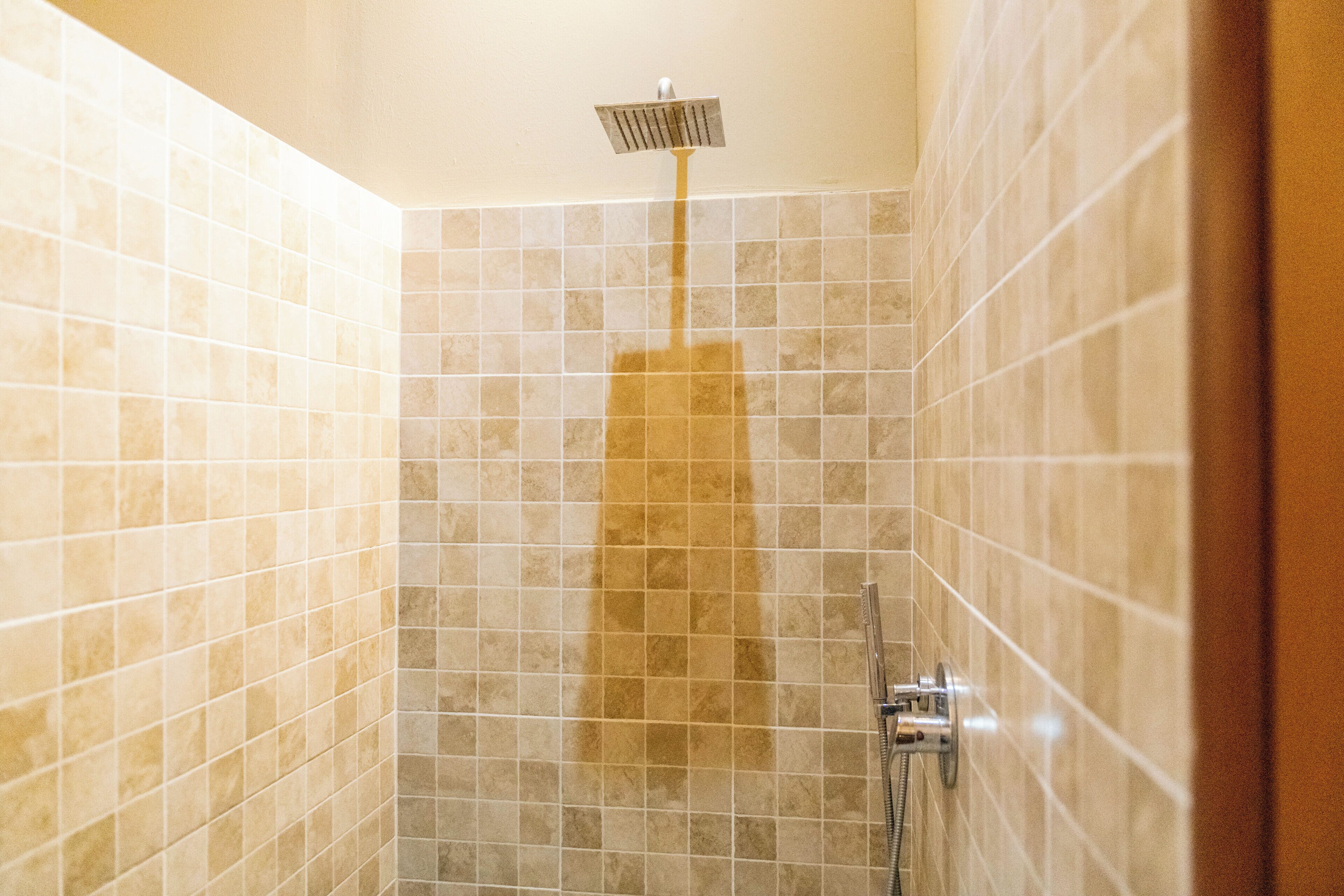 A tiled shower with a handheld showerhead.