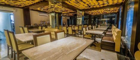 Un ristorante con diversi tavoli e sedie, un pavimento in marmo e un soffitto decorato.