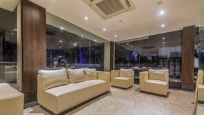 A modern interior with a sofa, chairs, and a marble floor. - Airport Guest House Guwahati (Guwahati)