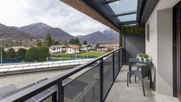 A balcony with a view of mountains, a table with chairs, and solar panels. - Studio 'Como's Lake Mountains Beb' with Mountain View, Private Terrace & Wi-Fi (Cremeno)