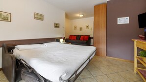 A hotel room with a bed, a sofa, a television, and a wooden cabinet. - Studio 'Como's Lake Mountains Beb' with Mountain View, Private Terrace & Wi-Fi (Cremeno)