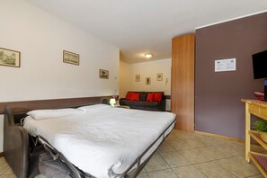 Ein Hotelzimmer mit einem Bett, einem Sofa, einem Fernseher und einem Holzschrank.