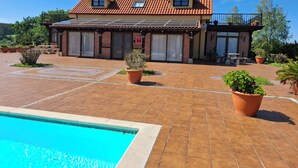 A two-story house with a tiled roof, a swimming pool, and potted plants. - San Roque village (Posadillo)