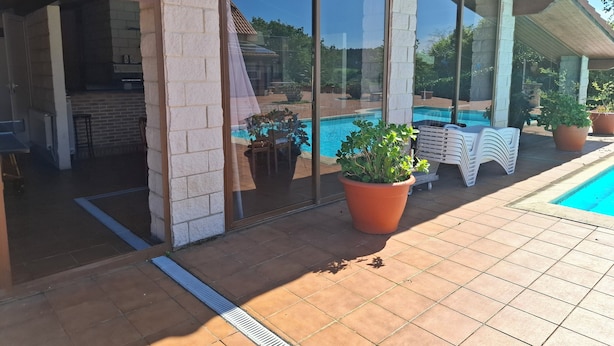 A covered outdoor area with a pool, potted plants, and a patio table. - San Roque village (Posadillo)