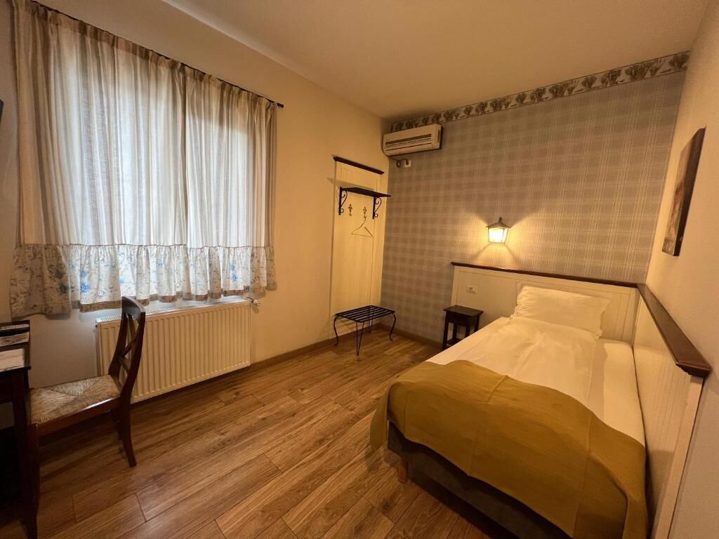 Ein Schlafzimmer mit einem Bett, einem Sessel, einem Heizkörper, einer Klimaanlage und einer Wandleuchte.