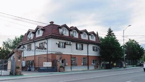 Un edificio a due piani con tetto in tegole rosse, diverse finestre e un cartello con la scritta 'Reverie'.