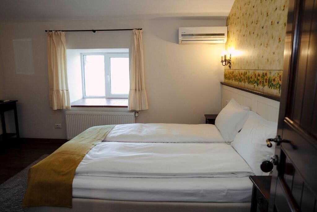 Una cama doble en una habitación con ventana, aire acondicionado y un aplique de pared.