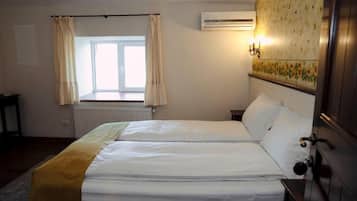 Una cama doble en una habitación con ventana, aire acondicionado y un aplique de pared.
