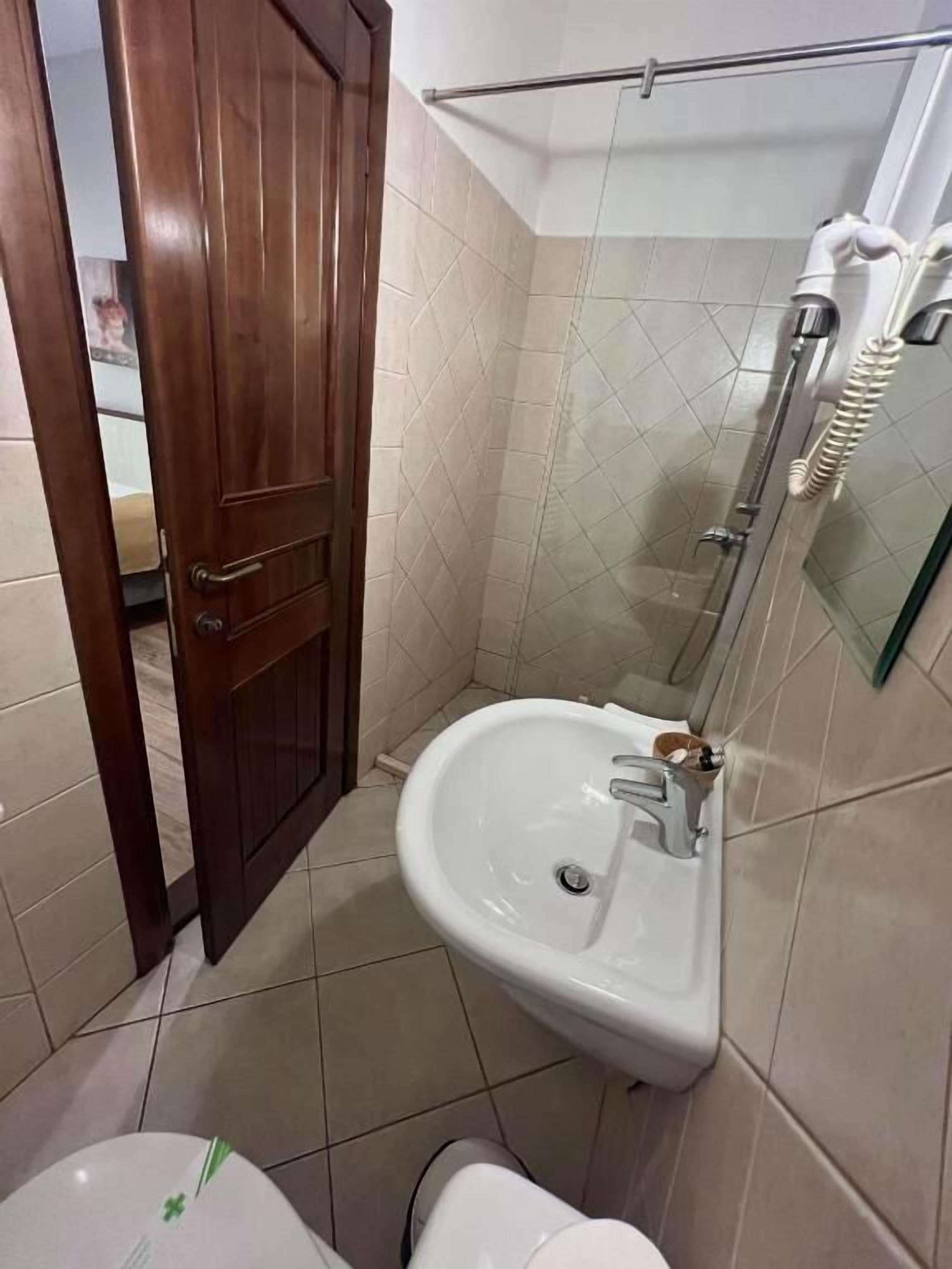 Une salle de bain avec une porte en bois, une douche avec une porte en verre, un lavabo et des toilettes.