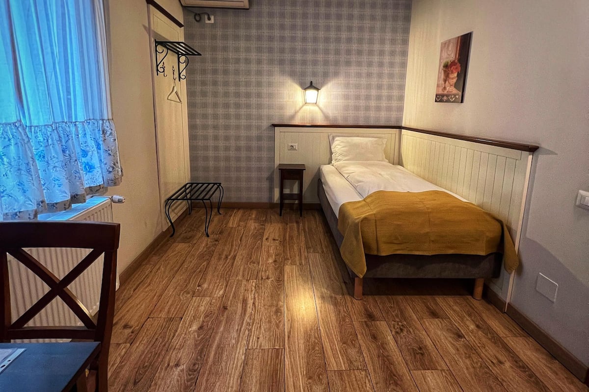 A small, cozy room with a bed, a desk, and a chair.
