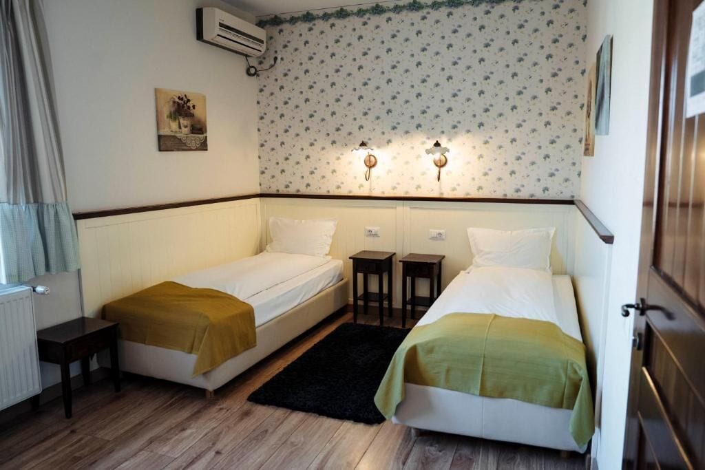 Une chambre d’hôtel avec deux lits, une petite table, un tapis noir et un climatiseur fixé au mur.