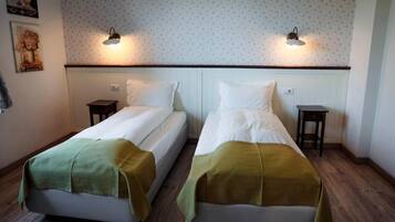 A room with two beds, each with a bedside table and a lamp.